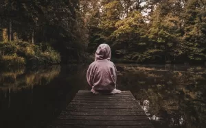 a person sitting on a dock looking at the water, childhood loneliness